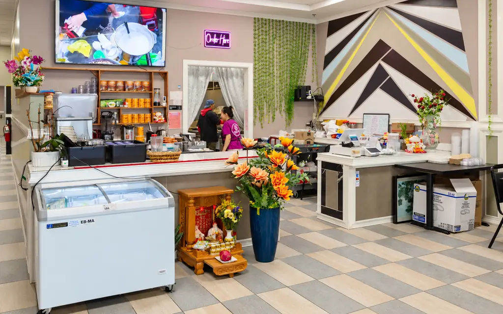 The order counter at Elisa Pho with fresh flowers and a menu screen